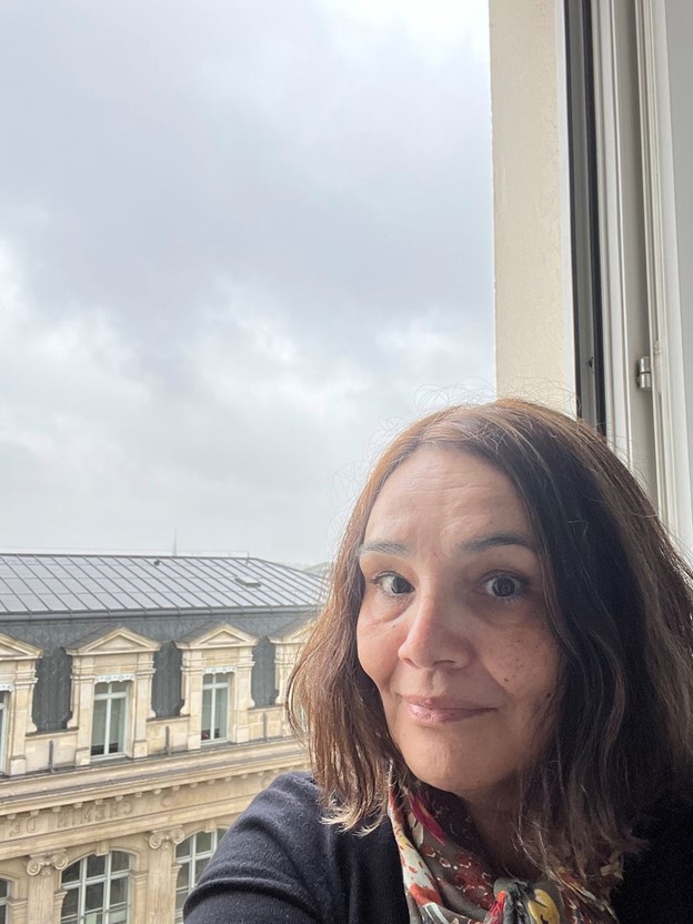 A photo of the author sitting in her hotel windowsill with the Gare du Nord behind her
