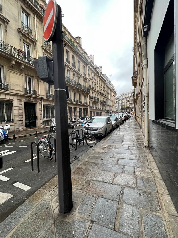 Another photo of a rainy street in Paris showing the cobblestone sidewalk